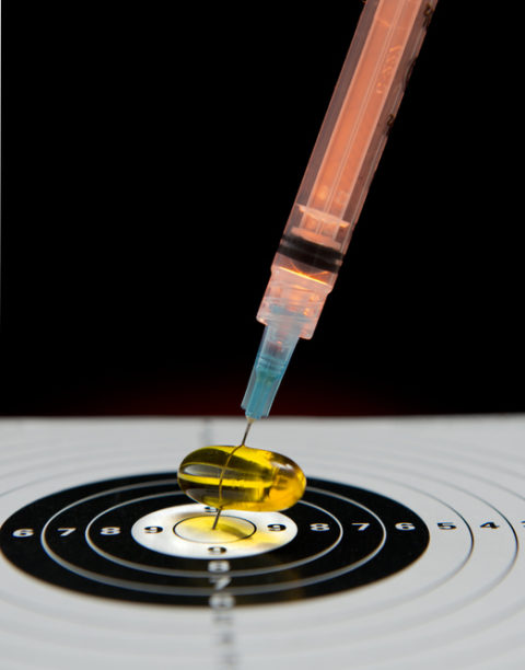 Targeting Medical Prescriptions in the form of pills or needle injections concept on black background. Image displays a hypodermic needle piercing a pill and hitting the bulls eye.
