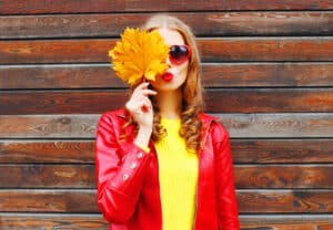 Woman in fall attire holding a leaf up to her face with clear skin from CO2 laser resurfacing